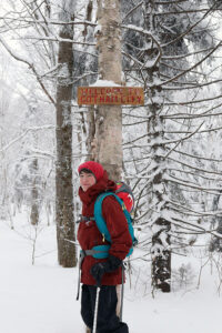 An image of Dylan below the Gotham City sign in the backcountry ski trail network at Bolton Valley Resort in Vermont