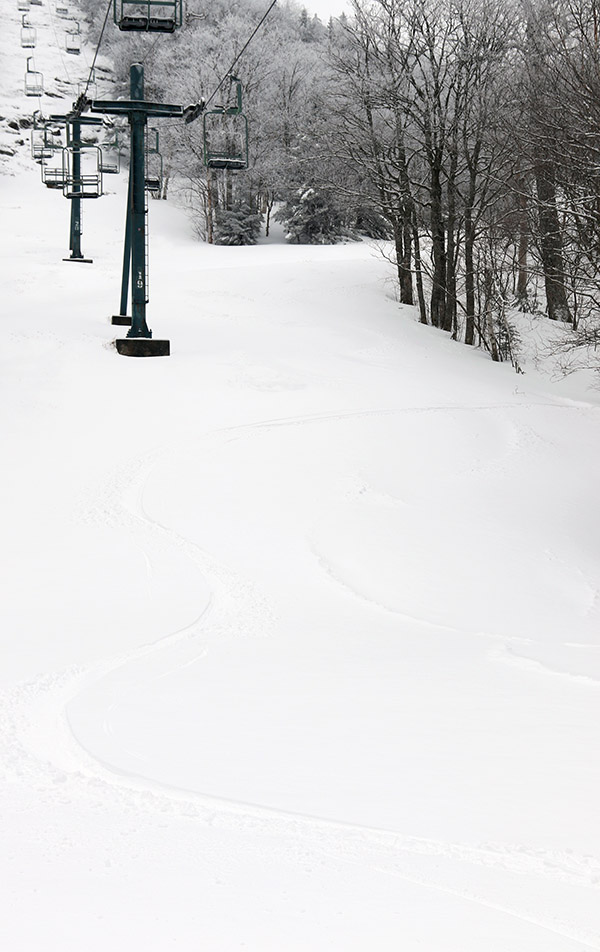 An image of ski tracks in powder snow on the Bolton Outlaw trail after an April snowstorm at Bolton Valley Ski Resort in Vermont
