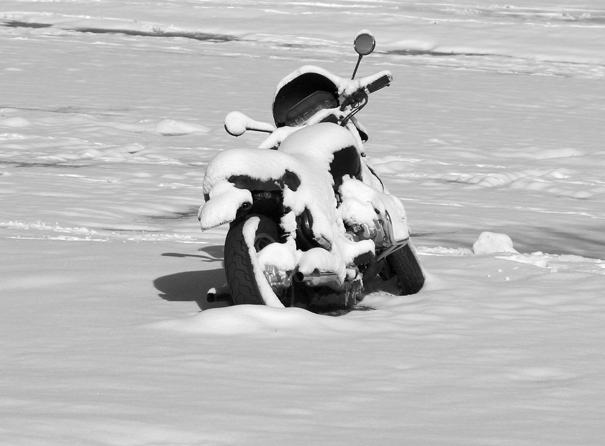 An image of a motorcycle covered in fresh snow from a mid-May snowstorm in the village parking lot at Bolton Valley Ski Resort in Vermont