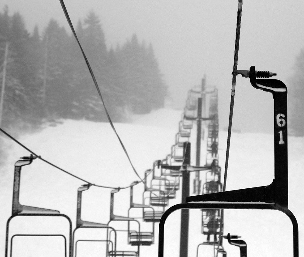 An image of the Mid Mountain Double Chair disappearing into the clouds on a snowy morning at Bolton Valley Ski Resort in Vermont