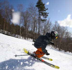An image of Ty skiing down the Showtime trail with spring snow at Bolton Valley Ski Resort in Vermont
