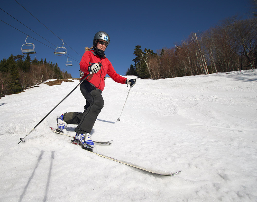 An image of Erica Telemark skiing in spring snow on a sunny day at Bolton Valley Ski Resort in Vermont
