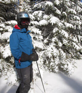 An image of Erica standing by some snowy evergreens after an April snowstorm at Bolton Valley Ski Resort in Vermont