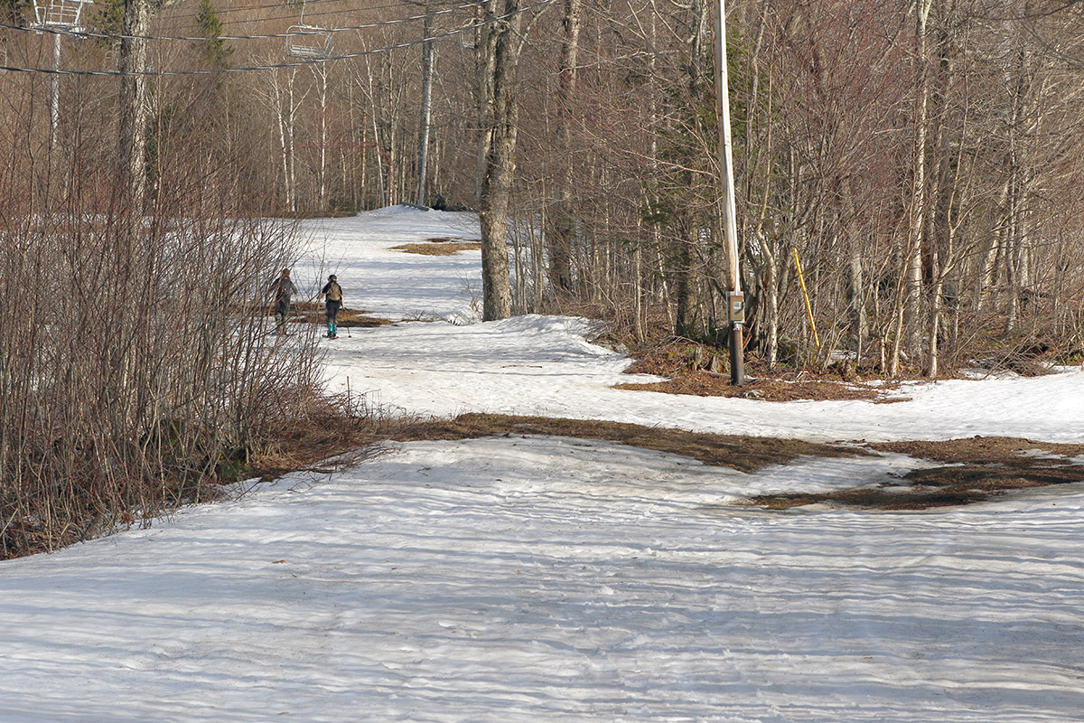 An image of a couple of skiers ascending on skins through the Hide Away Terrain Park on an April day at Bolton Valley Ski Resort in Vermont