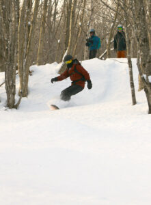 An image of Dylan riding powder snow on his snowboard during a tour of the Nordic & Backcountry Network at Bolton Valley Resort in Vermont