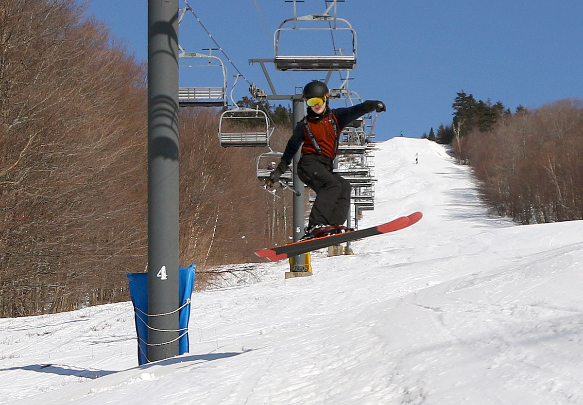 An image of Dylan performing a jump on his skis in soft spring snow on the Showtime trail at Bolton Valley Ski Resort in Vermont