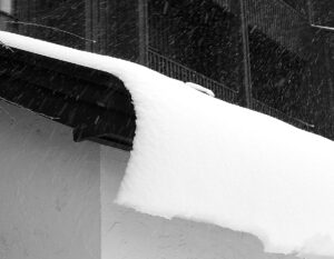 An image of snow from an April snowstorm curling off a roof at Bolton Valley Ski Resort in Vermont  