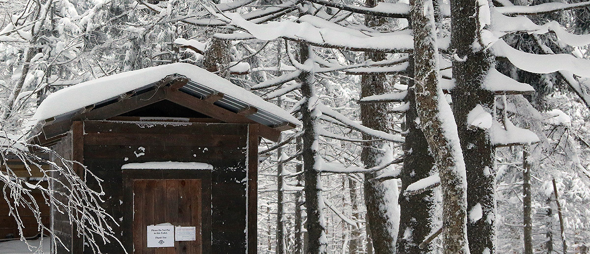 An image showing recent December snow covering tree branches and structures in the Bryant Cabin area of the Nordic and Backcountry Network at Bolton Valley Resort in Vermont