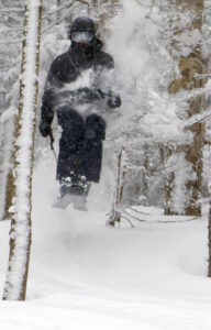 An image of Parker blasting his way through a tree while tree skiing in powder after a storm at Bolton Valley Resort in Vermont