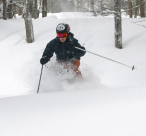 An image of Ty spraying powder while skiing during Winter Storm Quest at Bolton Valley Ski Resort in Vermont