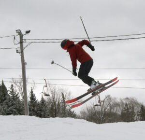 An image of Dylan performing a 360 ski jump in the Valley Road terrain park after a late March snowstorm at Bolton Valley Ski Resort in Vermont