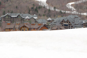 An image of the base area of Spruce Peak at Stowe Mountain Resort with some of the lower ski slopes in the foreground.