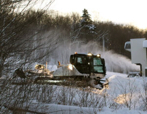 An image of a snowcat with a snow gun in the background at the main base area of Bolton Valley Ski Resort in Vermont