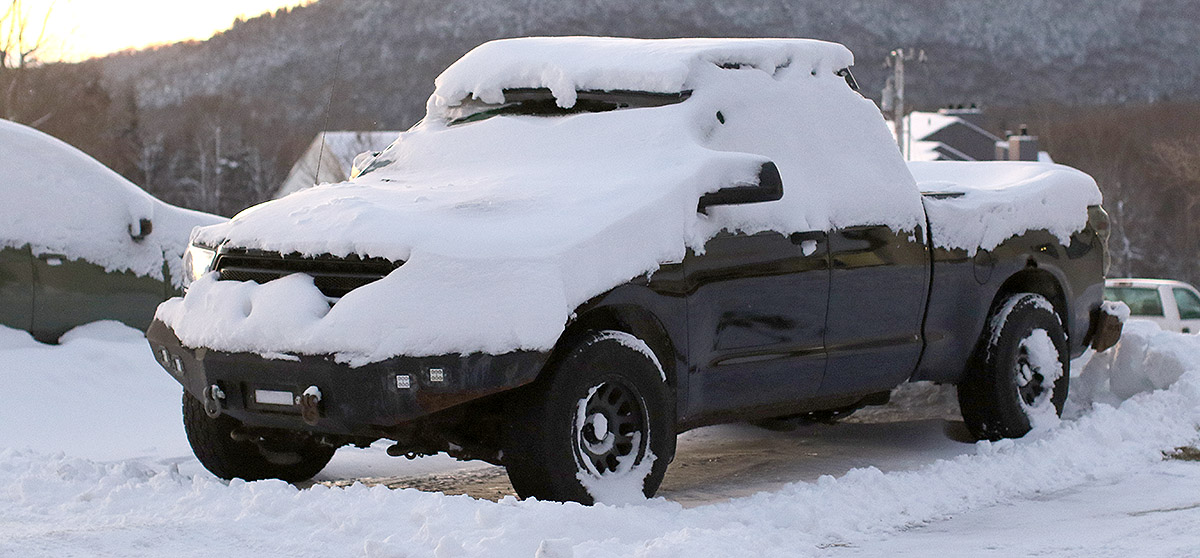 An image of a pickup truck covered in snow from recent November snowstorms in one of the parking lots at Bolton Valley Ski Resort in Vermont