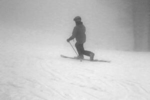An image of Erica Telemark skiing on soft snow with low clouds on the Bear Run trail at Bolton Valley Ski Resort in Vermont