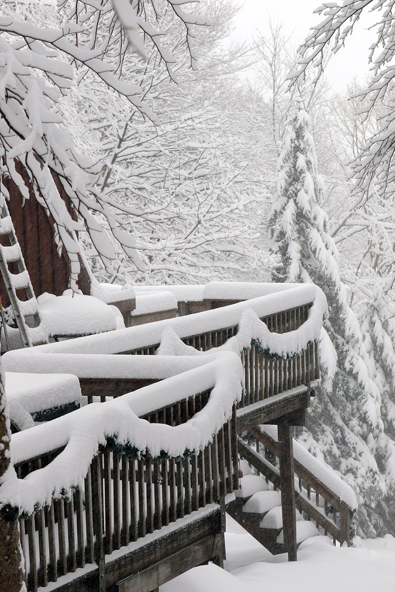 An image of the deck of a house covered in snow during a December snowstorm at Bolton Valley Ski Resort in Vermont