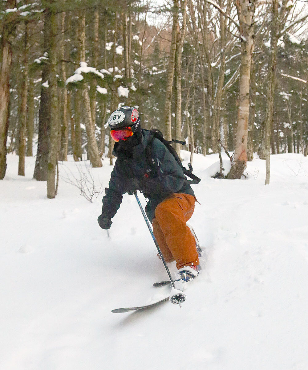 An image of Ty Telemark skiing in powder in mid-December in one of the glade areas on the Nordic and Backcountry Network at Bolton Valley Ski Resort in Vermont
