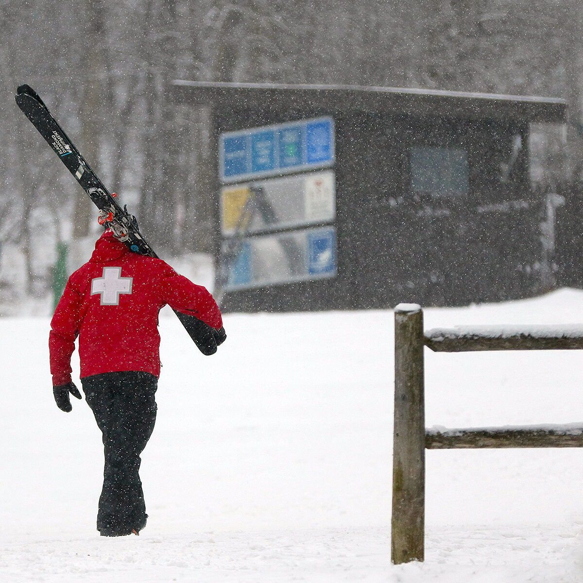 An image of a ski patroller walking through snowfall during a January storm in the main base area of Bolton Valley Ski Resort in Vermont