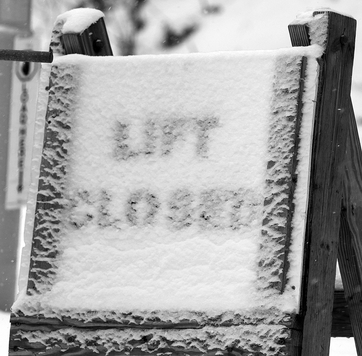 An image of a "Lift Closed" sign coated with a bit of fresh snow in early January at the base of the Wilderness Double Chairlift at Bolton Valley Ski Resort in Vermont