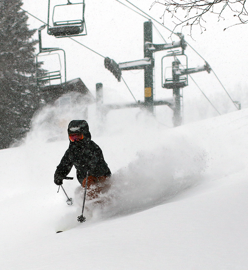 An image of Ty Telemark skiing in powder on the Wilderness Lift Line with the Wilderness Double Chairlift in the background as heavy snow falls from Winter Storm Heather at Bolton Valley Ski Resort in Vermont