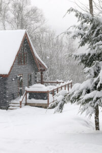 An image a cabin in heavy snowfall during a February snowstorm near the parking area for the Catamount Trail along the Bolton Valley Access Road below Bolton Valley Ski Resort in Vermont