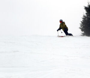 An image of Jay making a Telemark turn as he drops into a run in spring snow on the slopes of the Timberline area at Bolton Valley Ski Resort in Vermont 