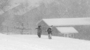 An image of two skiers walking through heavy snowfall during a February Alberta Clipper snowstorm near the base area of Bolton Valley Ski Resort in Vermont