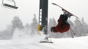 An image of Dylan halfway through a backflip on skis during a March snowstorm at Bolton Valley Ski Resort in Vermont