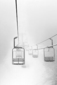 An image of the upper portion of the Wilderness Double Chairlift disappearing into the clouds on a March ski day at Bolton Valley Ski Resort in Vermont