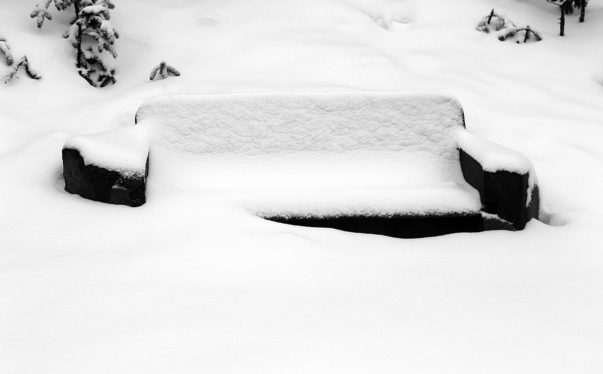 An image of an outdoor bench covered in snow form a mid-March storm at Bolton Valley Ski Resort in Vermont