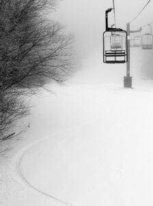 An image of ski turns in powder snow underneath the Wilderness Double Chairlift after a modest mid-March snowfall at Bolton Valley Ski Resort in Vermont