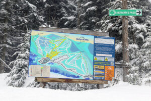 An image showing a trail map sign and some recent snow accumulations from a mid-March storm at the Vista Summit area of Bolton Valley Ski Resort in Vermont