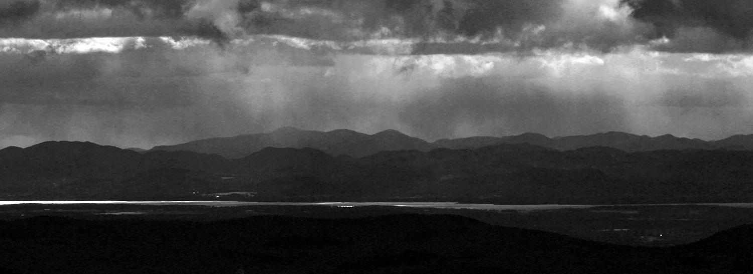 An image of snow squalls crashing out in the Adirondack Mountains of New York during a March ski day with variable weather as viewed from the slopes of Bolton Valley Ski Resort in Vermont