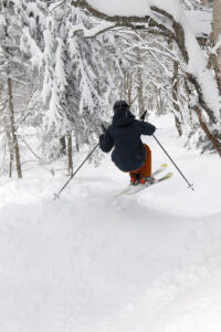 An image from behind of Ty diving into the Outlaw Woods as we ski the third day of Winter Storm Tormund in April 2024 at Bolton Valley Ski Resort in Vermont