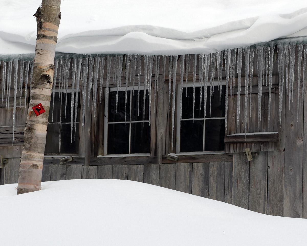 An image of The Bryant Cabin adorned with picturesque icicles and snow in mid-March during a ski tour on the Nordic and Backcountry Network at Bolton Valley Ski Resort in Vermont