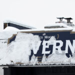 An image of the James Moore Tavern sign covered in fresh snow from an Alberta Clipper system on Christmas Eve at Bolton Valley Ski Resort in Vermont