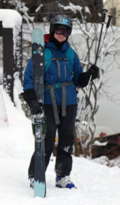 An image of Erica standing with her Telemark skis after a ski tour during a November lake-effect snow event at Bolton Valley Ski Resort in Vermont