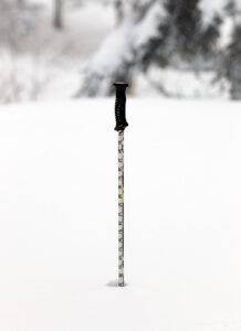 An image of a ski pole with measurement of the powder in the snowpack showing a depth of 24 inches during a backcountry ski tour on the Nordic and Backcountry Network of trails at Bolton Valley Ski Resort in Vermont