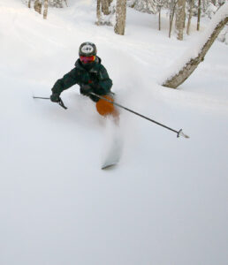 An image of Ty make a deep Telemark turn in powder during a backcountry ski tour in the Snow Hole area of Bolton Valley Ski Resort in Vermont