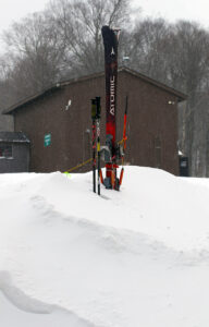 An image of Telemark skis and ski poles in a snow drift formed during a windy, long-duration January winter storm at Bolton Valley Ski Resort in Vermont