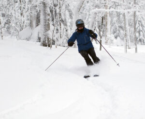 An image of Erica alpine skiing in powder snow in the Snow Hole area after a couple of long-duration winter storms in January at Bolton Valley Ski Resort in Vermont