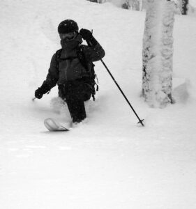 An image of Dylan Telemark skiing in deep powder snow in the trees during a January ski tour in the Gilpin Mountain/Domey's Dome area of the Jay Peak backcountry in Vermont