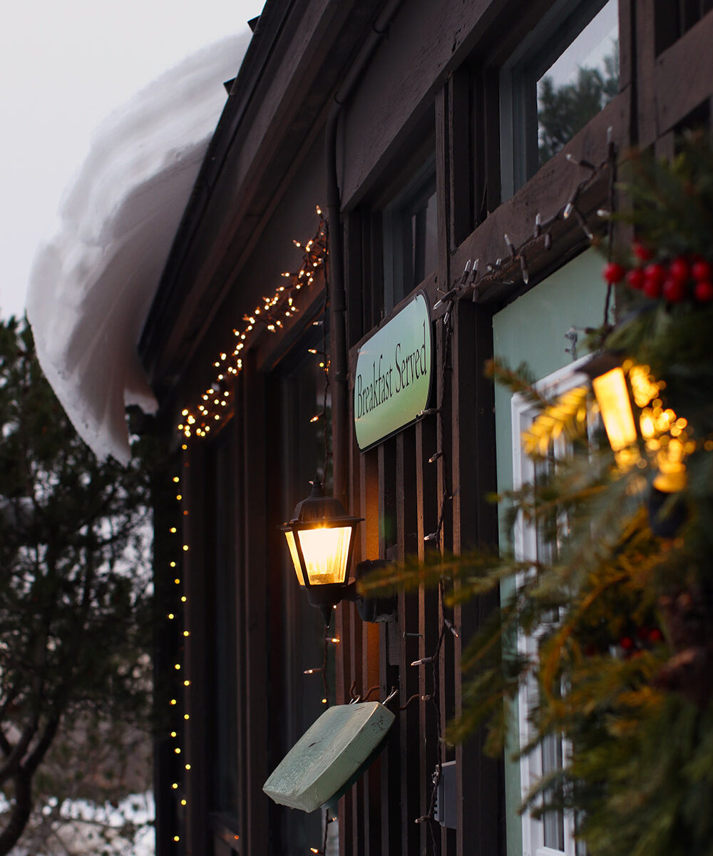 An image of snow curling off the roof of the Village Cafe during the holidays at Bolton Valley Ski Resort in Vermont